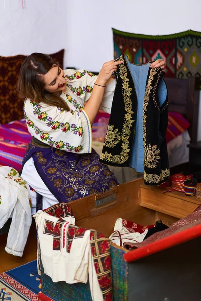 Молодая Румынская Женщина Открывает Свадебный Сундук Многими Традиционными Костюмами Примерить Лицензионные Стоковые Фото