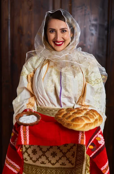 身着传统新娘流行服装的罗马尼亚年轻女子提供面包和盐作为欢迎 — 图库照片
