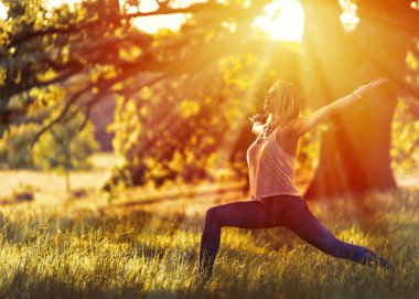 Sabahları yoga yapan bir kadın güneş yaşlı bir meşe ağacının dallarında parlarken.