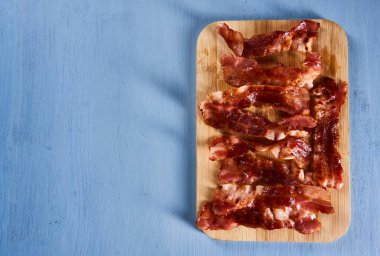 Strips of matured bacon fried and served on a wooden board