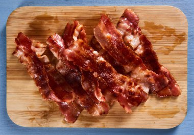 Strips of matured bacon fried and served on a wooden board