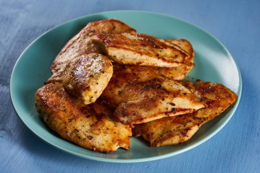 Seared chicken breast on a blue plate on a wooden board