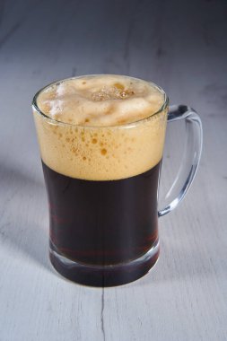 Foamy brown beer in a glass half a litre mug