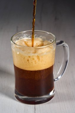 Pouring brown beer in a glass half a litre mug