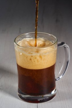 Pouring brown beer in a glass half a litre mug