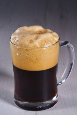 Foamy brown beer in a glass half a litre mug