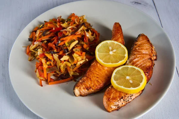 Salmon steaks and stir fry vegetables with lemon on a plate