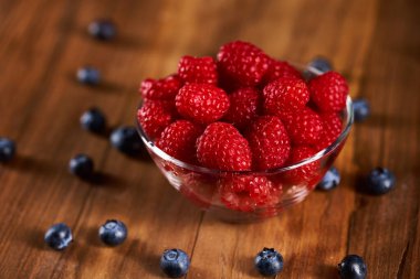 Raspberries and blueberries in bowls on a wooden board