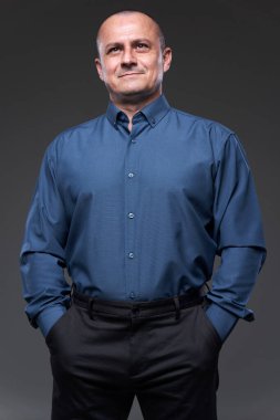 Confident businessman with hands in his pockets on gray background