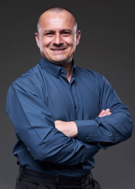Portrait of a smiling confident businessman with arms crossed on gray background