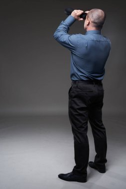 Businessman looking through binoculars, gray background