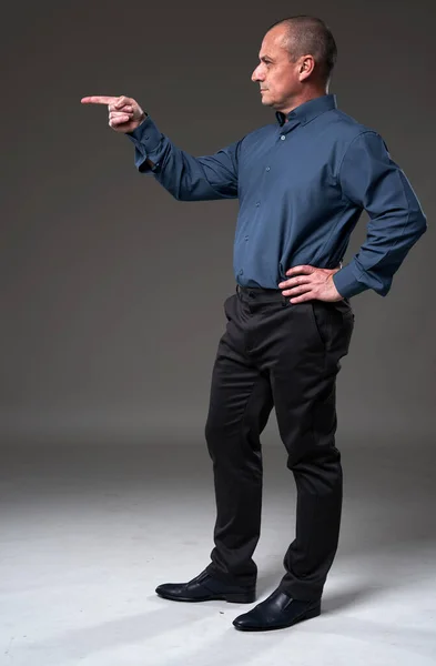 Full body profile portrait of a businessman pointing to the copyspace