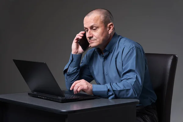 Зрелый Бизнесмен Работающий Своим Столом Ноутбуке Разговаривающий Мобильному Телефону Одновременно — стоковое фото
