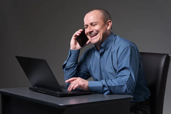 Зрелый Бизнесмен Работающий Своим Столом Ноутбуке Разговаривающий Мобильному Телефону Одновременно — стоковое фото