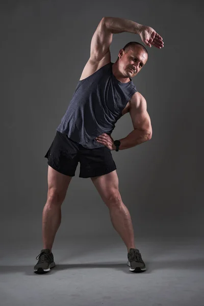 Full body shot of a mature man doing a fitness workout on gray background