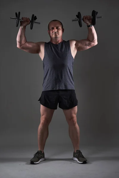 一个成熟男子在灰色背景下做健身锻炼的全身照 — 图库照片