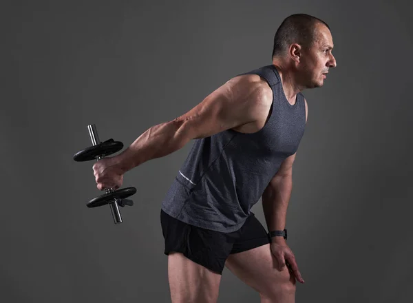 在灰色背景下进行健身训练的T恤和短裤中的成熟的高加索肌肉男子 — 图库照片