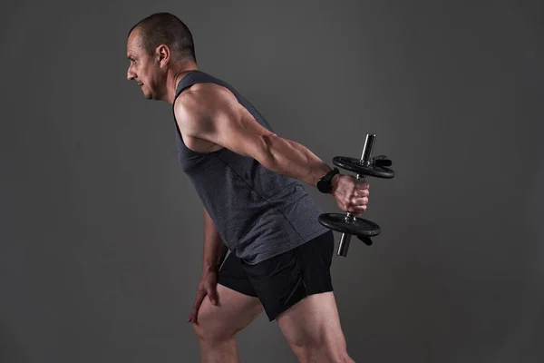 成熟したCaucasian筋肉男でティーとショートパンツ行いますフィットネストレーニング上の灰色の背景 — ストック写真