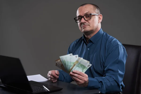 Ευτυχισμένος Ώριμος Επιχειρηματίας Που Κρατάει Μετρητά Κάθεται Στο Γραφείο Του — Φωτογραφία Αρχείου