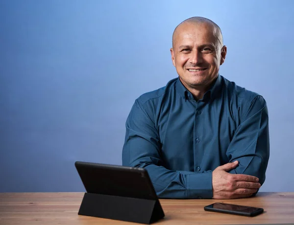 Boldog Üzletember Asztalánál Táblagépével Kék Háttérrel — Stock Fotó