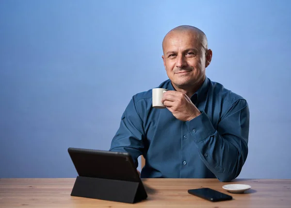 Šťastný Obchodník Pije Kávu Tabletem Před Sebou Svém Stole Přes — Stock fotografie