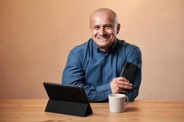 Šťastný Dospělý Obchodník Sedí Svého Stolu Telefon Tablet Šálek Kávy — Stock fotografie
