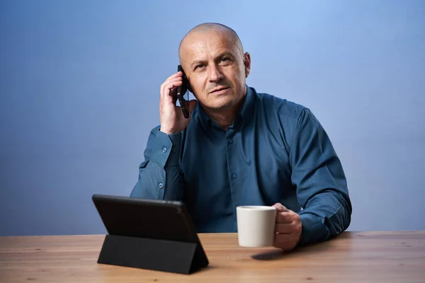 Podnikatel Dává Šálek Kávy Stolem Před Svým Tabletem Mluví Mobilním — Stock fotografie