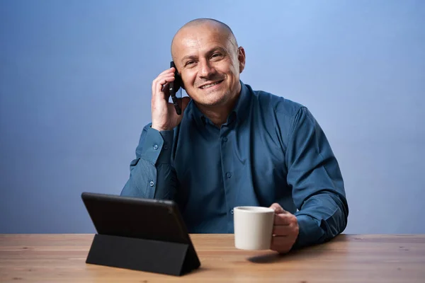 Podnikatel Dává Šálek Kávy Stolem Před Svým Tabletem Mluví Mobilním — Stock fotografie