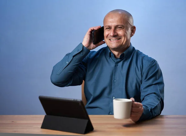 Бизнесмен Чашкой Кофе Своим Столом Перед Планшетом Разговаривает Мобильному Телефону — стоковое фото