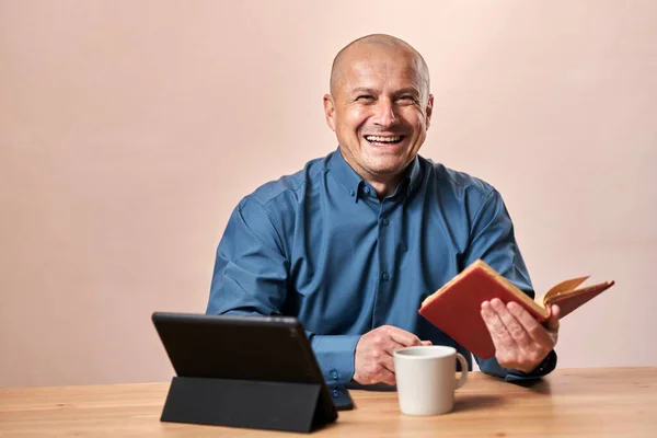 Homem Lendo Livro Bem Humorado Sua Mesa Com Café Tablet — Fotografia de Stock