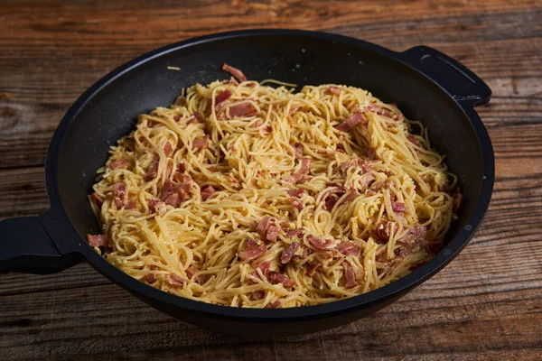 木製のトレイに鍋に豚肉ハムとパルメザンチーズとイタリアのカルボナーラパスタ — ストック写真