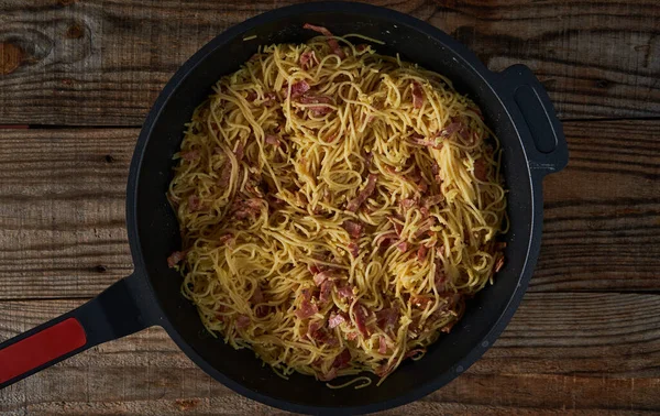 意大利卡拉面 锅中有猪肉火腿和意大利面 放在木盘上 — 图库照片
