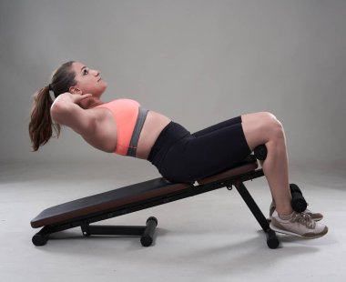 Kendine güveni tam ve kilolu genç bir kadın halterle spor yapıyor.