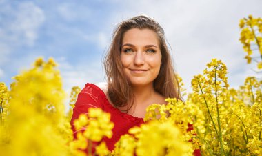 Kanola tarlasında mavi gözlü, güzel beyaz bir sarışının portresi. Çiçek açmış.