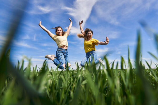 Two plus size girls jumping for joy and having fun in a wheat field