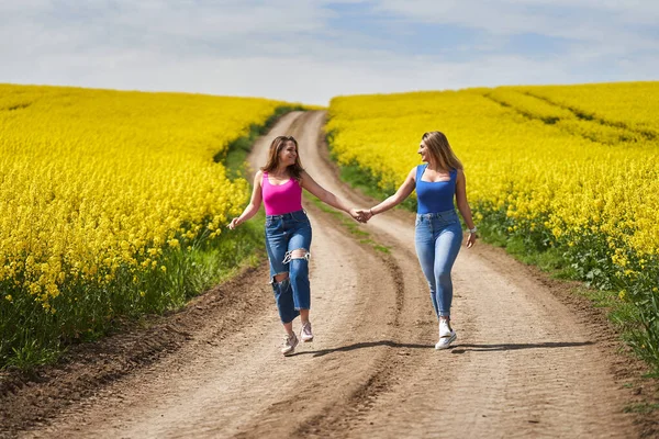 Two Size Girlfriends Joyfully Walking Dirt Road Blooming Canola Field — Stock Photo, Image
