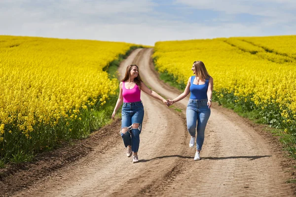 Två Storlek Flickvänner Glatt Promenader Grusväg Genom Blommande Raps Fält — Stockfoto