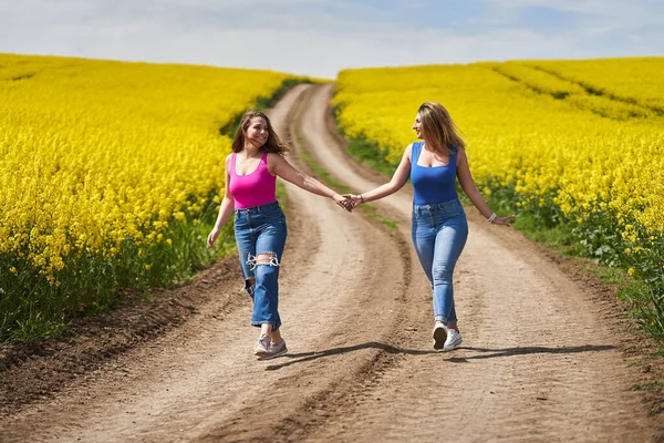 Two Size Girlfriends Joyfully Walking Dirt Road Blooming Canola Field — Stock Photo, Image