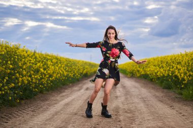 Baharın sonunda bir kanola tarlasında çiçeklerle süslenmiş güzel bir İspanyol kadının portresi.