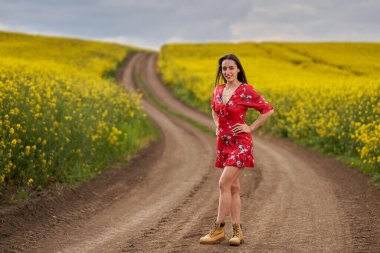 Baharın sonunda bir kanola tarlasında çiçeklerle süslenmiş güzel bir İspanyol kadının portresi.