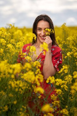 Baharın sonunda bir kanola tarlasında çiçeklerle süslenmiş güzel bir İspanyol kadının portresi.
