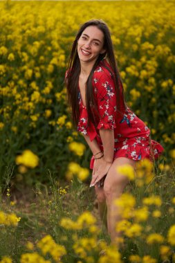 Baharın sonunda bir kanola tarlasında çiçeklerle süslenmiş güzel bir İspanyol kadının portresi.