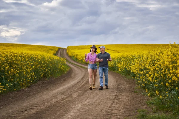 農家の夫婦は満開の菜の花畑を調べる — ストック写真