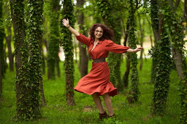 公園で幸せに踊る美しい成熟した巻き毛の女性の候補の肖像画 — ストック写真