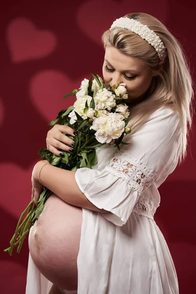 美しいです妊娠若いですブロンド女性でホワイトランジェリー上の赤背景 — ストック写真