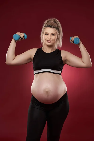 Mujer Embarazada Joven Haciendo Ejercicios Acondicionamiento Físico Sobre Fondo Rojo —  Fotos de Stock