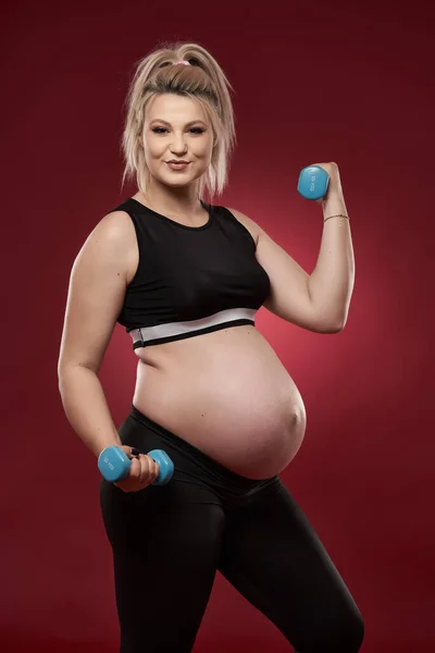 Jonge Zwangere Vrouw Doet Fitness Oefeningen Rode Achtergrond Studio Shot — Stockfoto