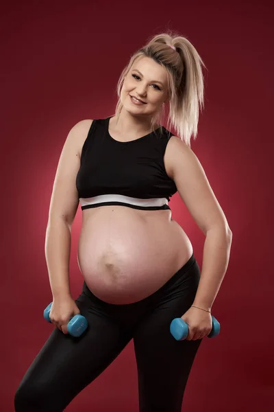 Mujer Embarazada Joven Haciendo Ejercicios Acondicionamiento Físico Sobre Fondo Rojo — Foto de Stock