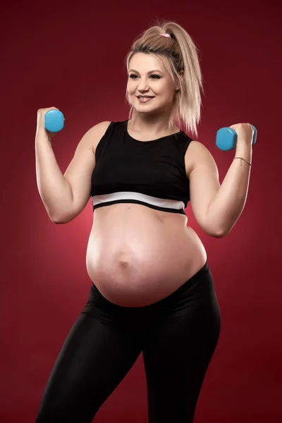 Jeune Femme Enceinte Faisant Des Exercices Fitness Sur Fond Rouge — Photo