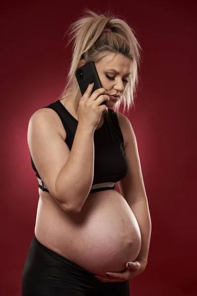 Hamile Kadın Cep Telefonuyla Konuşuyor Stüdyo Fotoğrafı Kırmızı Arkaplanda — Stok fotoğraf